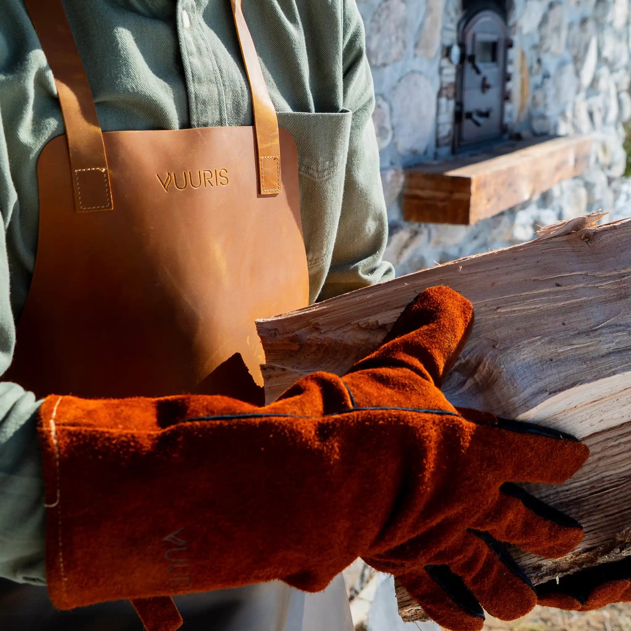 Close up of person holding logs of wood wearing the Vuuris gloves and the Vuuris apron