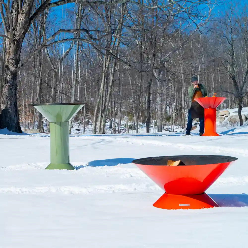A wide shot of a field full of snow with a red house in the background with 3 Vuuris products that are on fire, a orange Tiger, green Sage in the large base setup and one orange Tiger in small base setup with founder using blowpoke on Vuuris in background